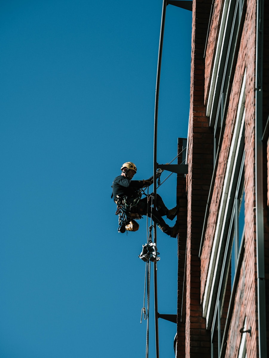 A man with harness safety on a high wire working on a building